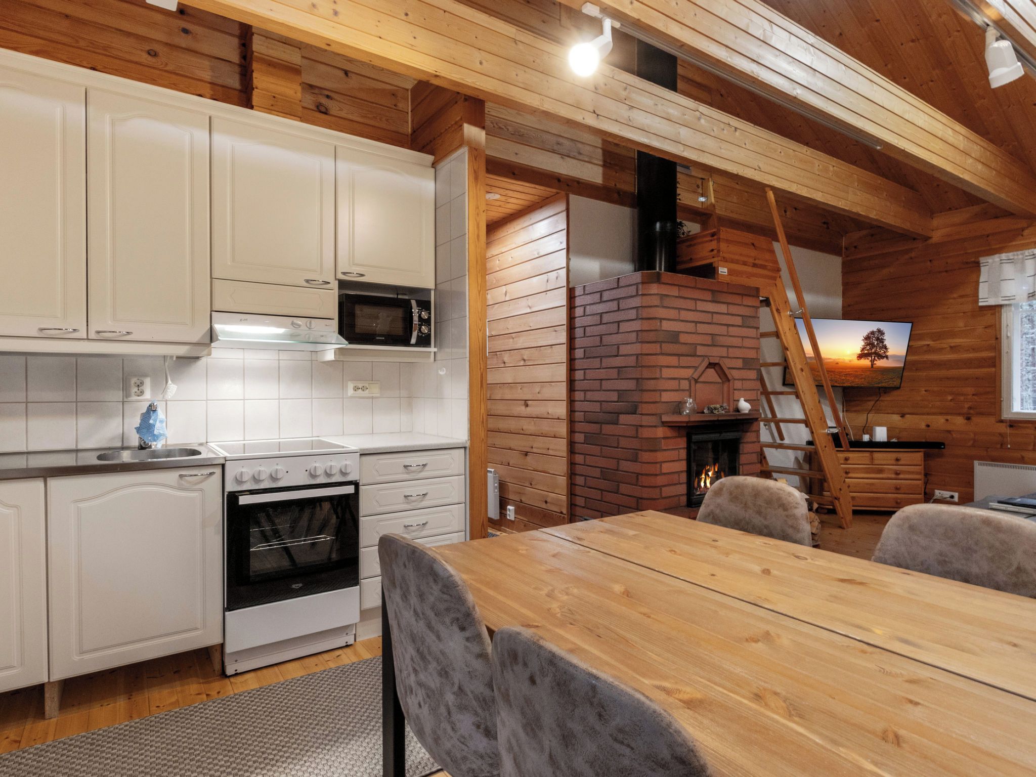 Una cucina con mobili bianchi, un forno a microonde, un forno e un camino in mattoni.