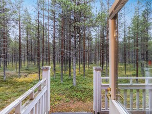 Puinen terassi, joka johtaa korkeiden mäntyjen reunustamalle metsäiselle alueelle.