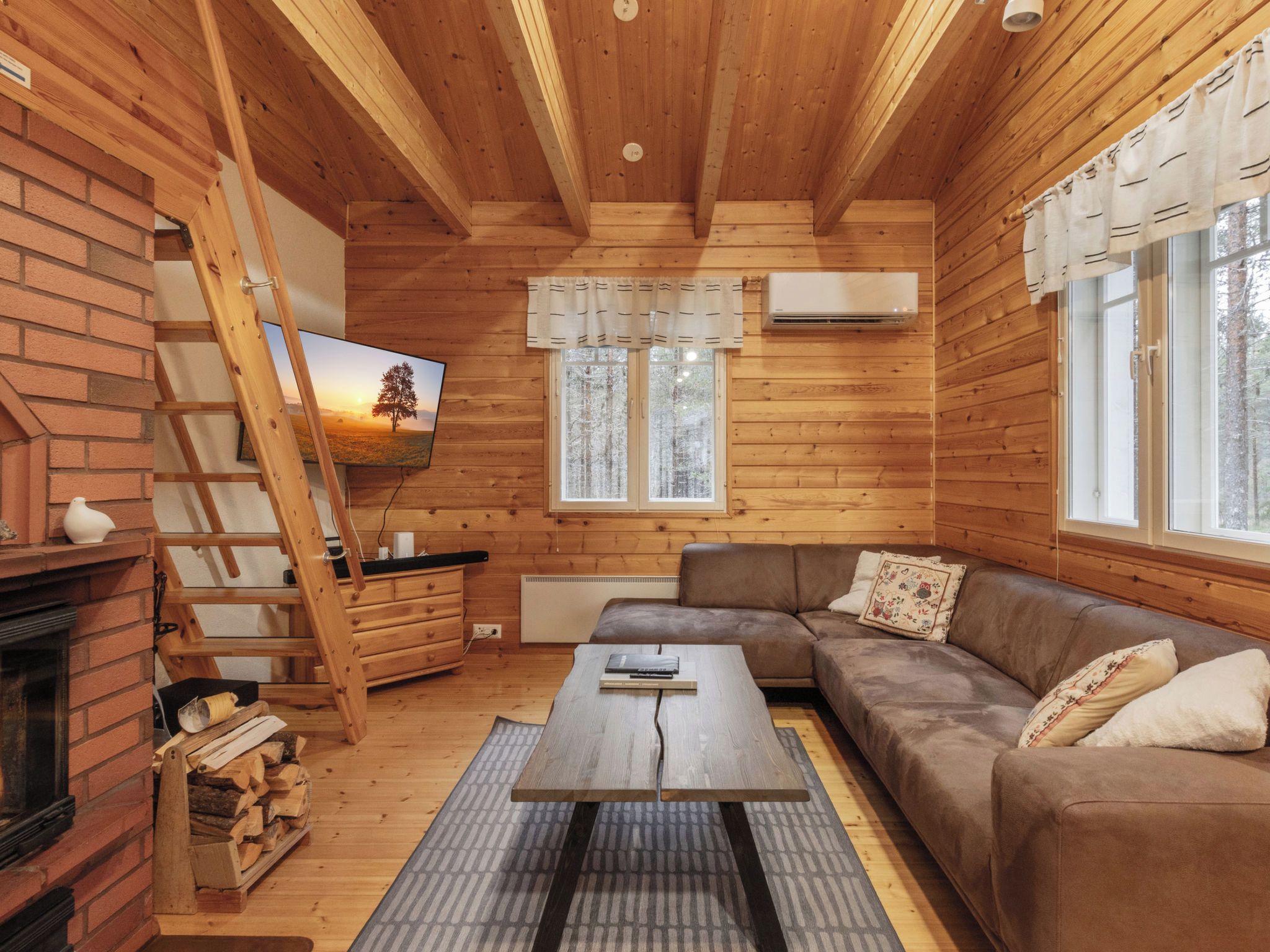 Interior acogedor de una cabaña con chimenea, un sofá, una mesita de centro y un cuadro.