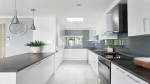 A modern kitchen with white cabinetry, a black countertop, and a large window providing natural light.