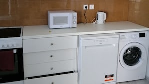 Une cuisine compacte équipée d’un four à micro-ondes, d’une machine à café, d’un lave-vaisselle et d’un four.