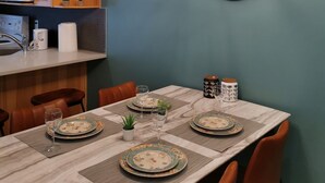A dining area with a table set for four, surrounded by chairs, and a kitchen area with wooden cabinets and a microwave.