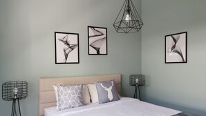 A bedroom with a bed, two bedside tables, and three wall-mounted abstract art pieces.
