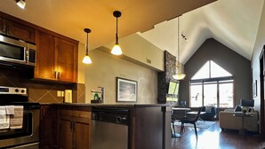 Une cuisine moderne avec des meubles en bois, des appareils en acier inoxydable et des luminaires suspendus.