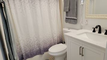 A bathroom with a white toilet, a white sink with black faucets, and a shower curtain with a geometric pattern.