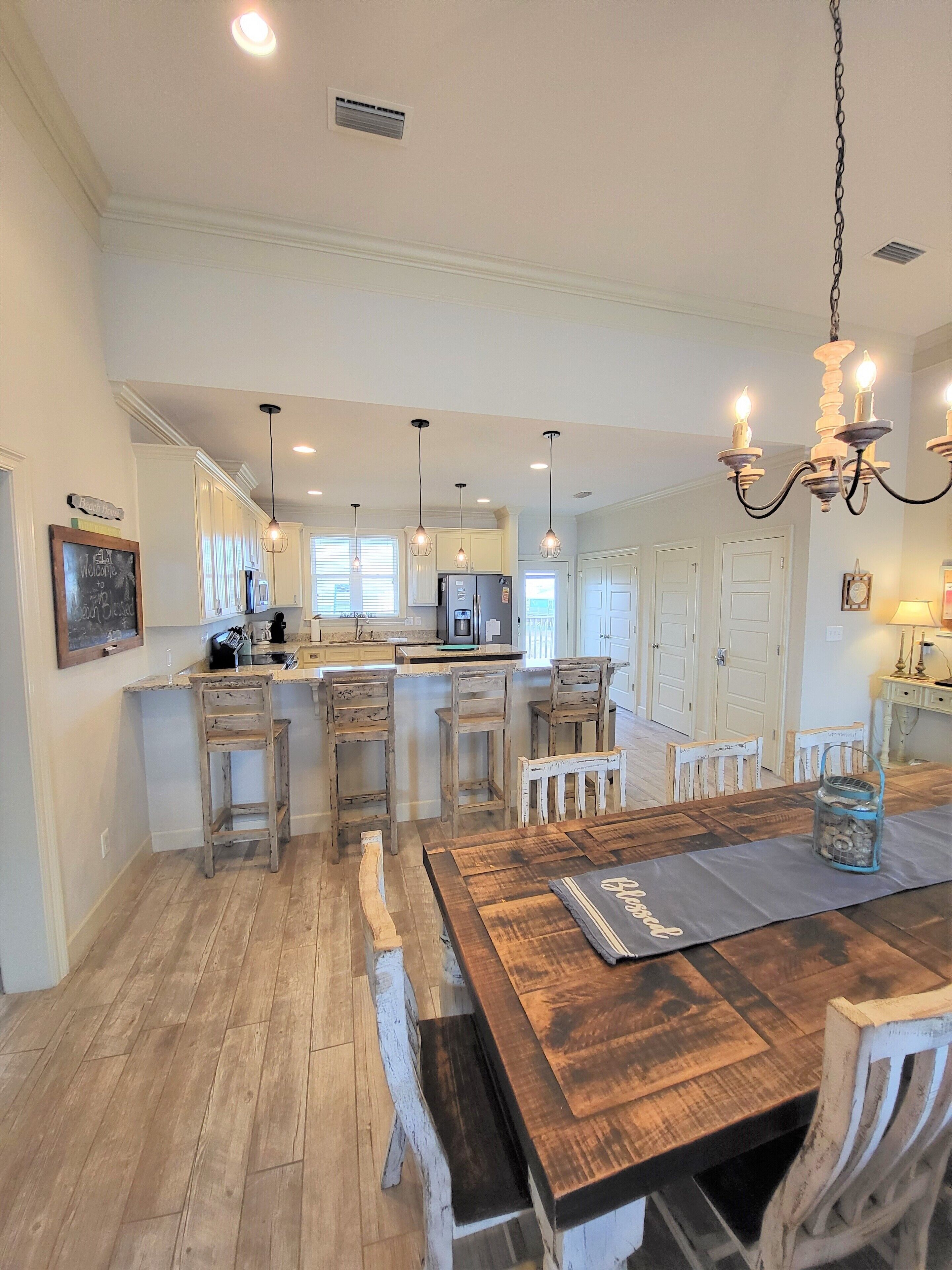 Une cuisine spacieuse avec un îlot central en bois, des luminaires suspendus et un lustre.