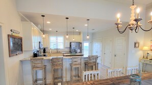 A spacious kitchen with a wooden island, pendant lights, and a chandelier.