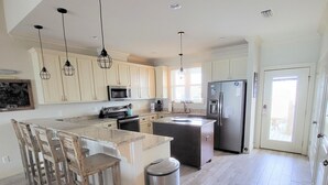 A spacious kitchen with a large island, wooden flooring, and modern appliances.