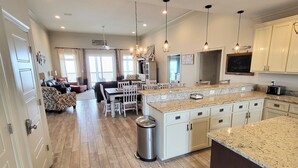 A spacious kitchen with a large island, wooden flooring, and modern pendant lighting.