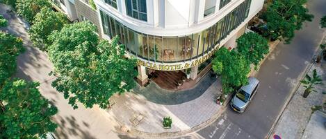 Un hotel de varios pisos con fachada curva, entrada central y vista a la calle.