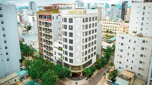 A multi-story hotel with a prominent 'Capecia' sign, surrounded by other buildings and greenery. - Capecia Danang Hotel & Apartment (Da Nang)