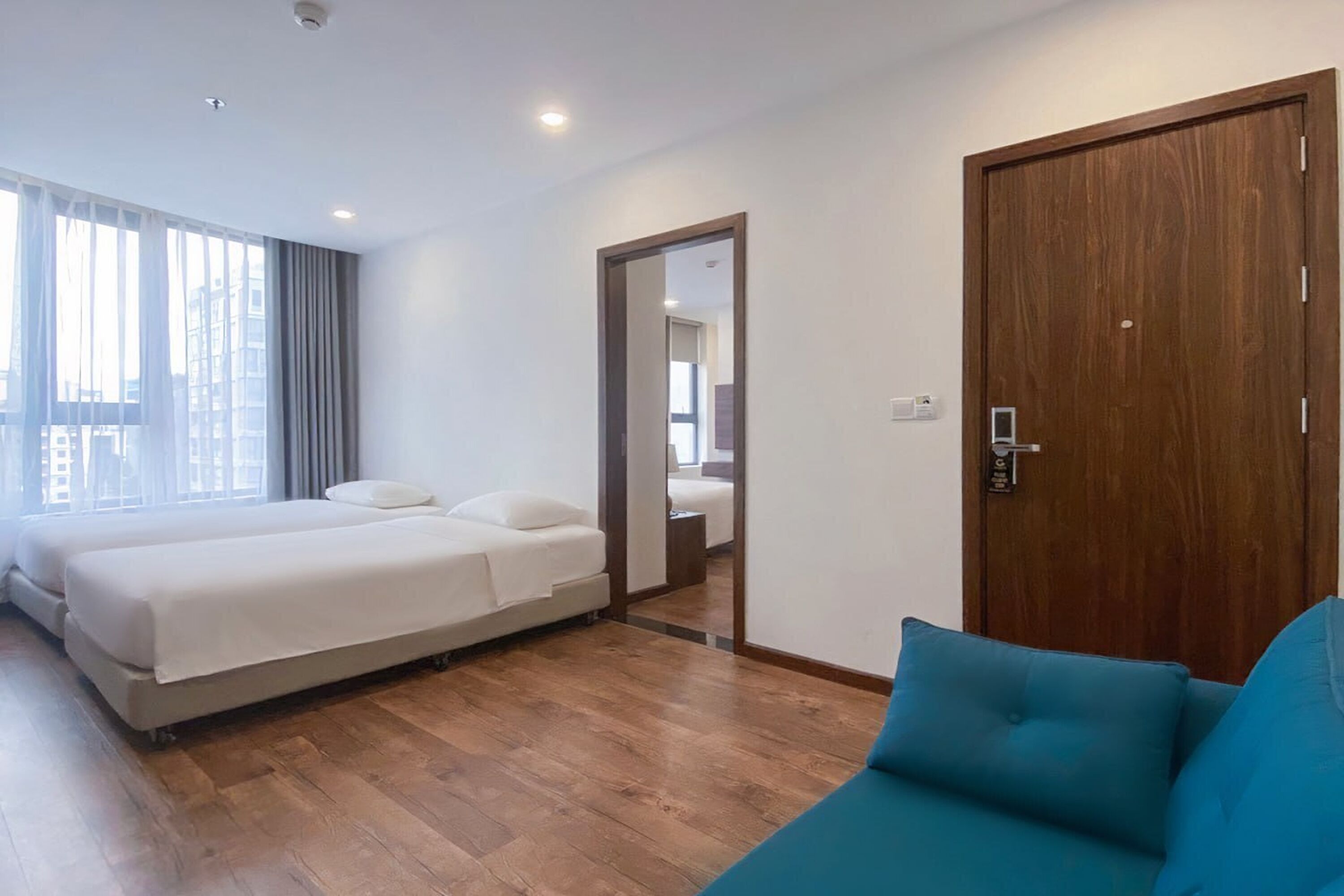 Una habitación de hotel moderna con una cama grande, un sofá y una puerta de madera.
