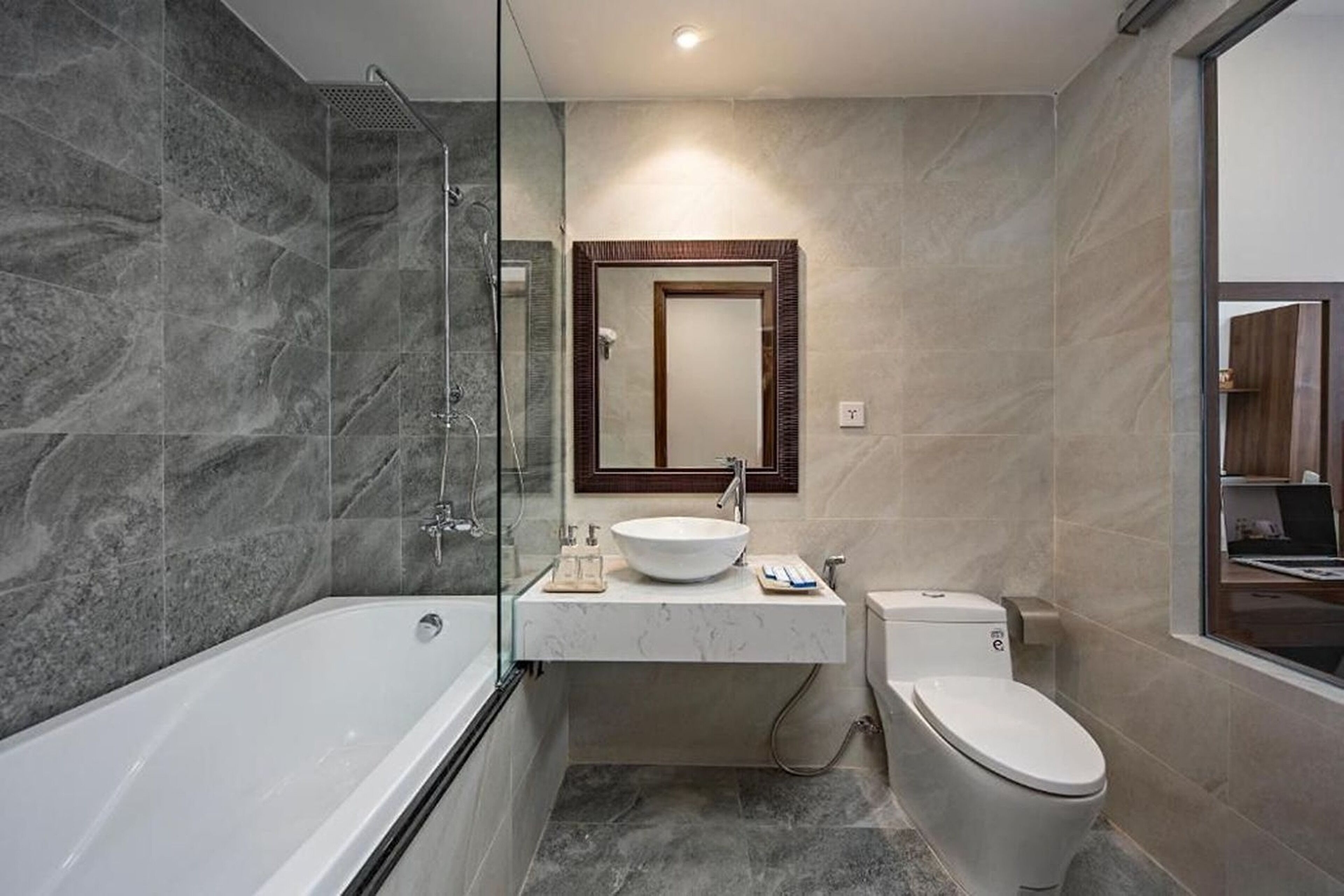A modern bathroom with a glass-enclosed shower, a freestanding bathtub, a sink with a mirror above, and a toilet.
