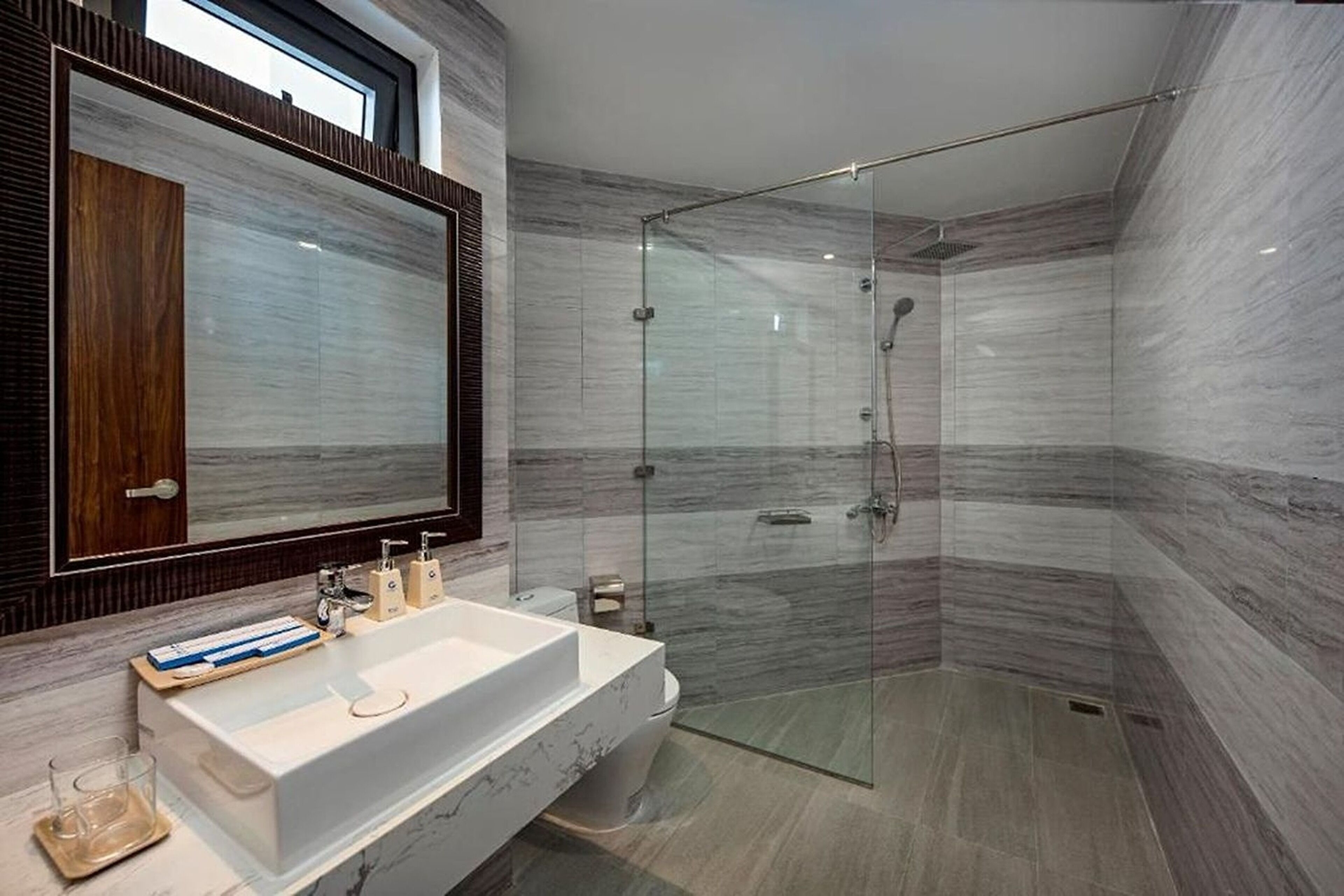 A modern bathroom with a large mirror, a glass-enclosed shower, and a marble sink.