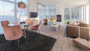 Una sala de estar moderna con una mesa de comedor de vidrio, sillas rosas, un sofá y una chimenea.