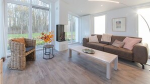 Una sala de estar amplia con ventanas grandes, una chimenea, un sofá y una mesa de centro.