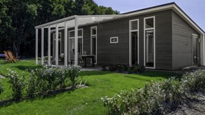 Una casa moderna con un porche cubierto, césped y jardín.