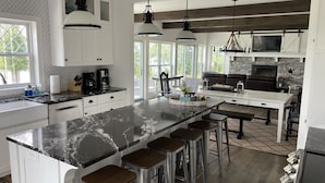 A modern kitchen with a large island, bar stools, and a stone backsplash.