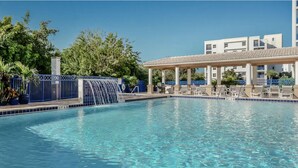 A swimming pool with a waterfall feature, lounge chairs, and a covered seating area.