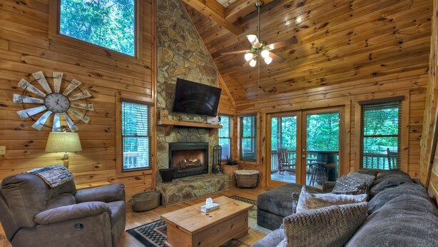 A cozy cabin interior with a stone fireplace, wooden walls, a comfortable sofa, and a television. - Serendipity - Cherry Log (Cherry Log)