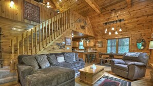 A cozy cabin interior with a wooden staircase, a sofa, a recliner, and a dining area. - Serendipity - Cherry Log (Cherry Log)