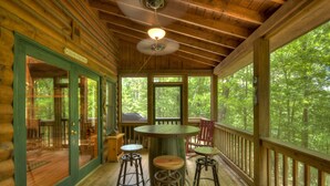 A wooden cabin with a porch, a round table, and four stools. - Serendipity - Cherry Log (Cherry Log)