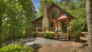 A log cabin with a stone chimney, wooden deck, and an American flag. - Serendipity - Cherry Log (Cherry Log)