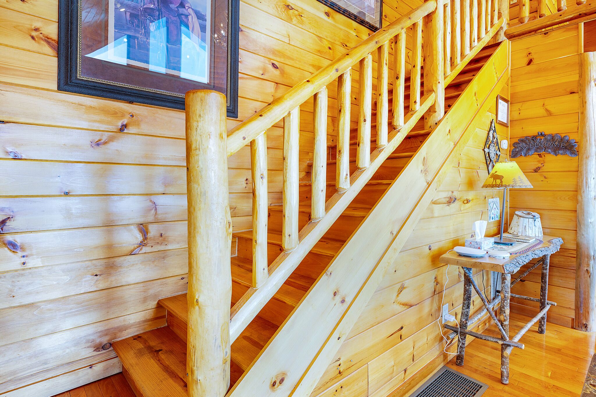 A wooden staircase with a handrail and a small table with a lamp and a sign that says "WELCOME".