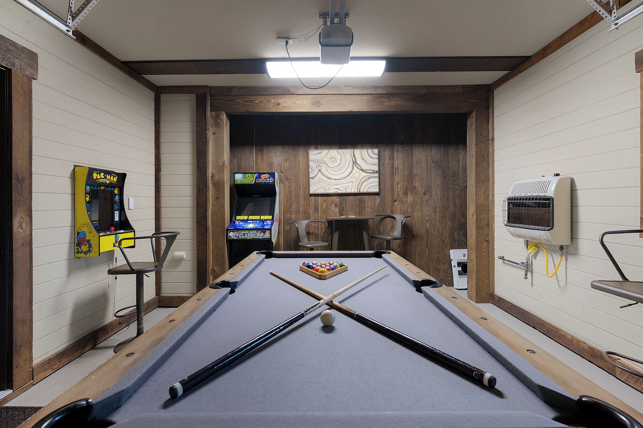 Mesa de billar con proyector, juegos de arcade y una mesa de billar dispuesta.