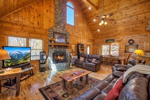 A cozy cabin interior with a stone fireplace, leather furniture, a television, and a dining area. - Amazing View - Mineral Bluff (Mineral Bluff)