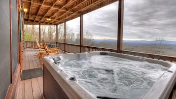A hot tub under a wooden pergola with a view of the mountains.