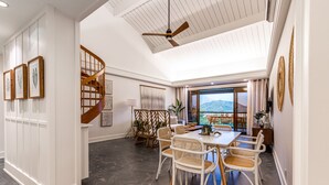 A spacious dining area with a wooden staircase, wicker chairs, and a large window offering a mountain view. - Hanalei Bay Resort Suite 9304, 5, 6 (Hanalei Bay Hideaway) AC! (Princeville)