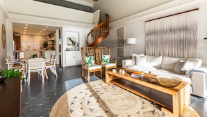 A spacious living area with a wooden coffee table, white sofa, and wicker chairs. A spiral staircase leads to an upper level. - Hanalei Bay Resort Suite 9304, 5, 6 (Hanalei Bay Hideaway) AC! (Princeville)