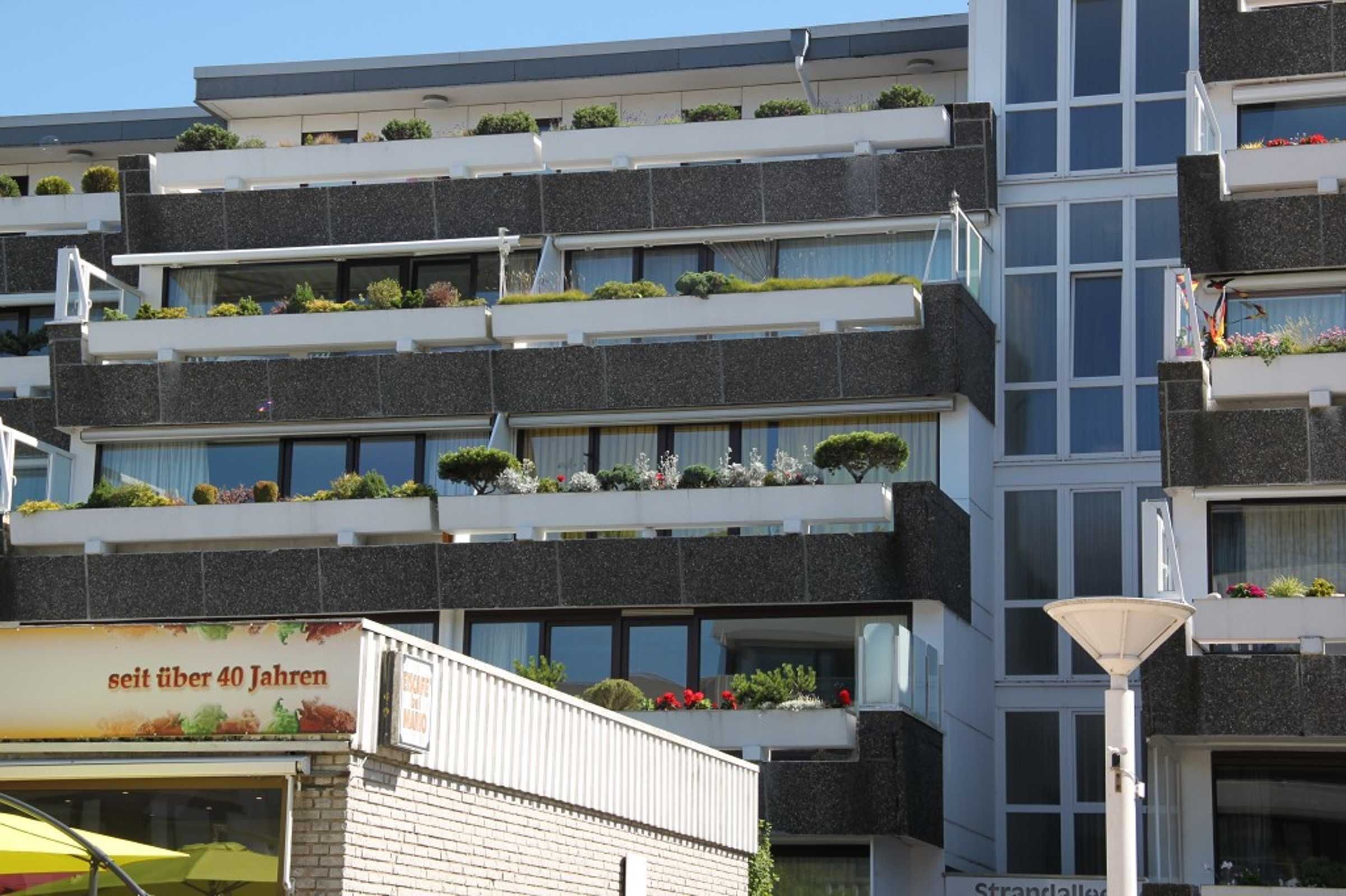 Un edificio de varios pisos con balcones, cada uno decorado con plantas y flores.