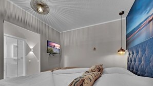A modern bedroom with a large bed, a television, and a painting on the wall. - Seaside SA 140 - Seaside, 2 Zi, 65m², Balkon, Meerblick, 2. OG Fahrstuhl (Scharbeutz)