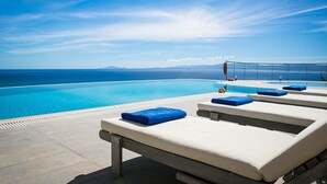 Zona de piscina con sillones de descanso y vista despejada al océano.