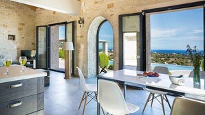 Una cocina moderna con una isla grande, sillas blancas y vistas al mar.
