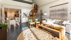 A spacious living area with a wooden coffee table, white sofa, and wicker chairs. A spiral staircase leads to an upper level. - Hanalei Bay Resort 9305 (Hanalei Bay Hideaway) AC! (Princeville)