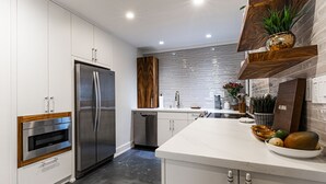 A modern kitchen with stainless steel appliances, a white countertop, and wooden accents. - Hanalei Bay Resort 9305 (Hanalei Bay Hideaway) AC! (Princeville)