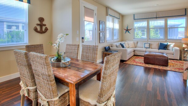 A living room with a wooden dining table, wicker chairs, a sofa, and a star decoration on the wall. - Our Beach Adventure - Oyhut Bay Seaside Village (Ocean Shores)