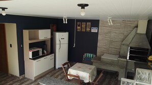 Une cuisine compacte équipée d’un réfrigérateur, d’un four à micro-ondes et d’une petite table à manger avec des chaises.