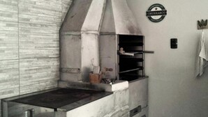 Une cuisine avec un mur en briques, une cheminée, une horloge et une enseigne sur laquelle on peut lire « CHURRASCO ».
