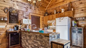 Una cocina acogedora con paredes de madera, encimera de piedra y un refrigerador.