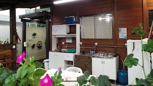 Une cuisine rustique avec des murs en bois, un plan de travail blanc et une fenêtre ornée de rideaux à motifs floraux.