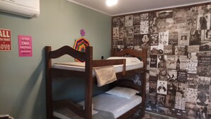 Une chambre avec un lit superposé, un mur recouvert de posters, un climatiseur Samsung et des panneaux d’affichage avec des messages motivants.