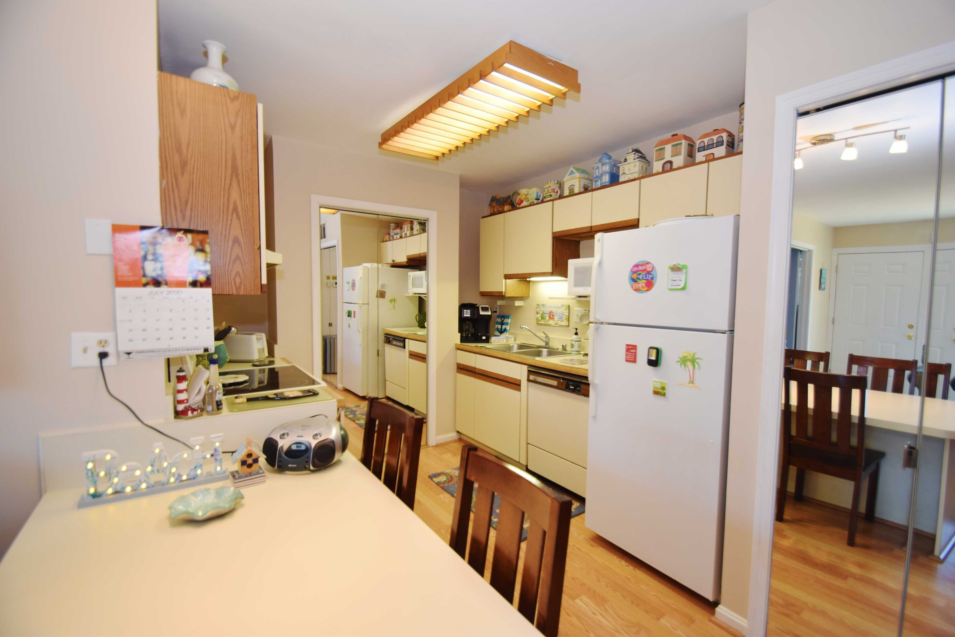 A compact kitchen with wooden cabinets, a refrigerator, a microwave, and a dining table with chairs.