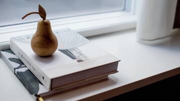 Un libro titulado “The Kinfolk” sobre un alféizar, con un objeto con forma de pera de madera encima.