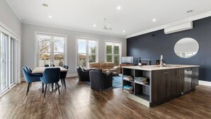 Eine moderne Küche mit Kochinsel, Essbereich mit Stühlen und ein Wohnzimmer mit Sofa.