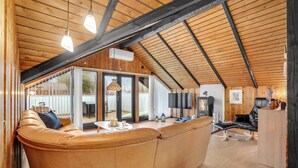 Una sala de estar acogedora con un amplio sofá de cuero, techo de madera y chimenea.