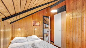 Un dormitorio con paredes de madera, una cama, una mesita de noche y un espejo.